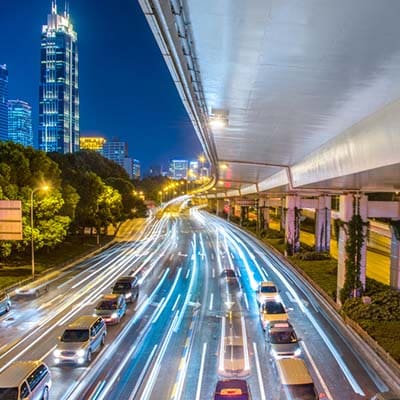 By optimizing websites and content, businesses can appear higher in search engines. Highway traffic at night, buildings in background.
