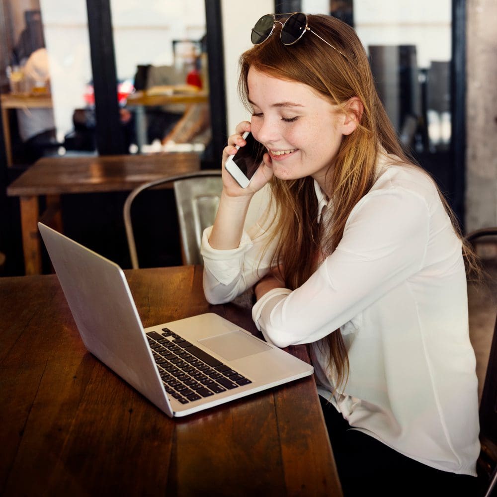 A woman is discussing the importance of local SEO on her cell phone at a table.