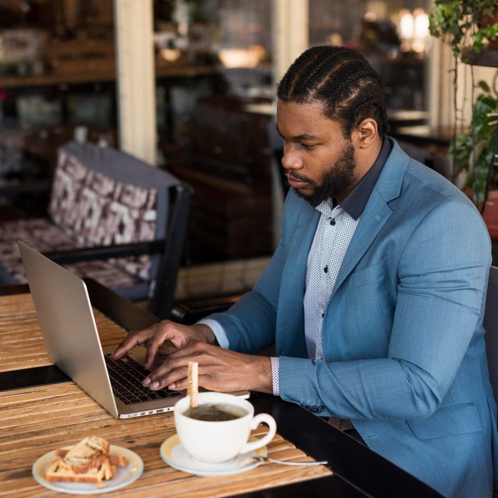 A man of African descent utilizing a laptop at a local cafe. A man of African descent utilizing a laptop at a local cafe.