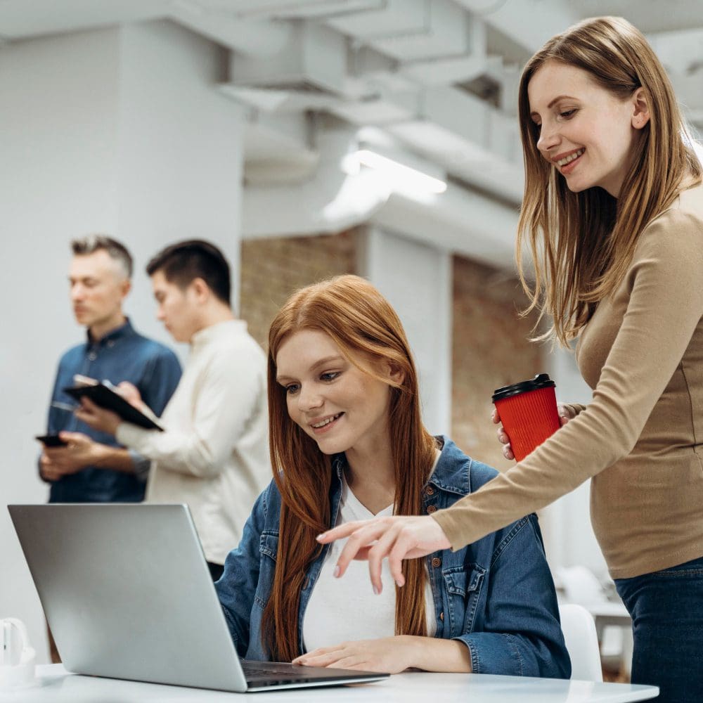 Two women engaging in local digital marketing on a laptop in an office setting. Two women engaging in local digital marketing on a laptop in an office setting.