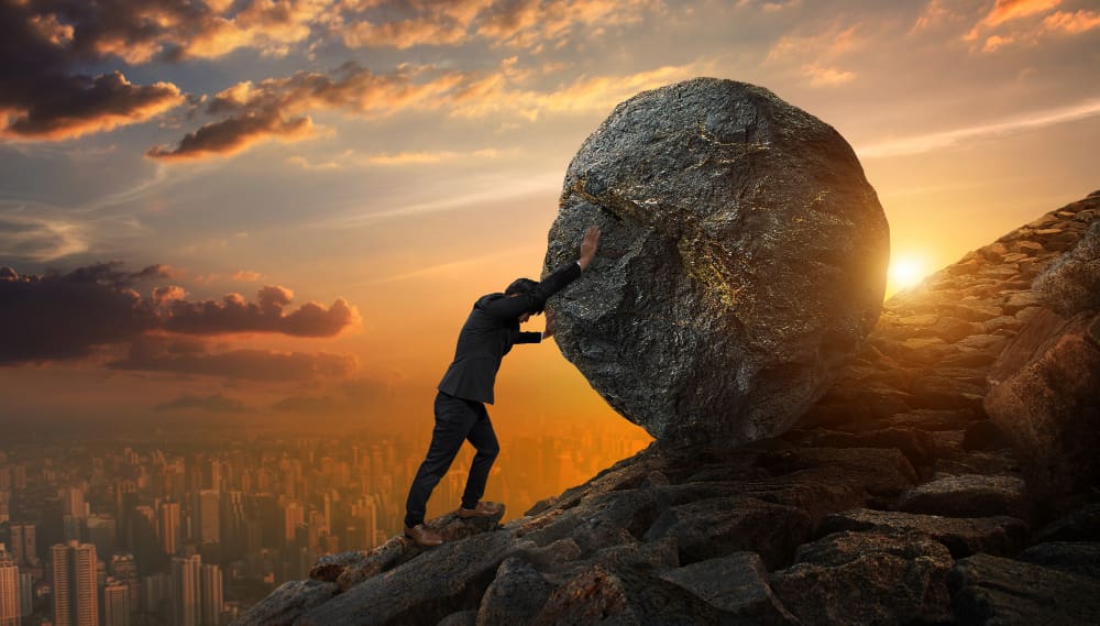 Local businesses are perfectly poised to conquer any obstacle in today's digital era. A businessman laboriously pushing a rock uphill.