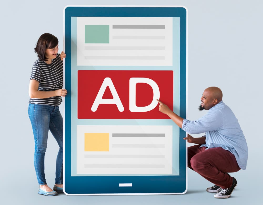 Online advertising is an effective way for businesses to reach their target audience. Two individuals examining a massive screen displaying an ad.