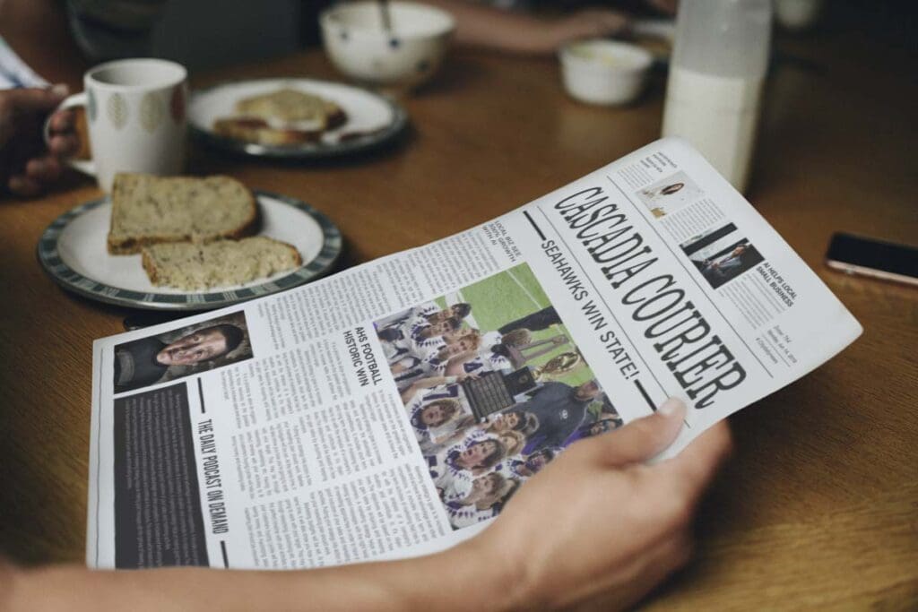 A person reading a newspaper on a table.